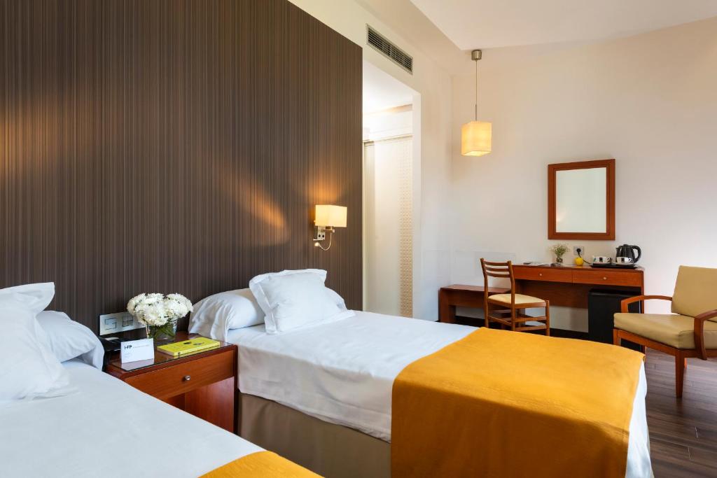 a hotel room with two beds and a desk at Hotel de Francia y París in Cádiz