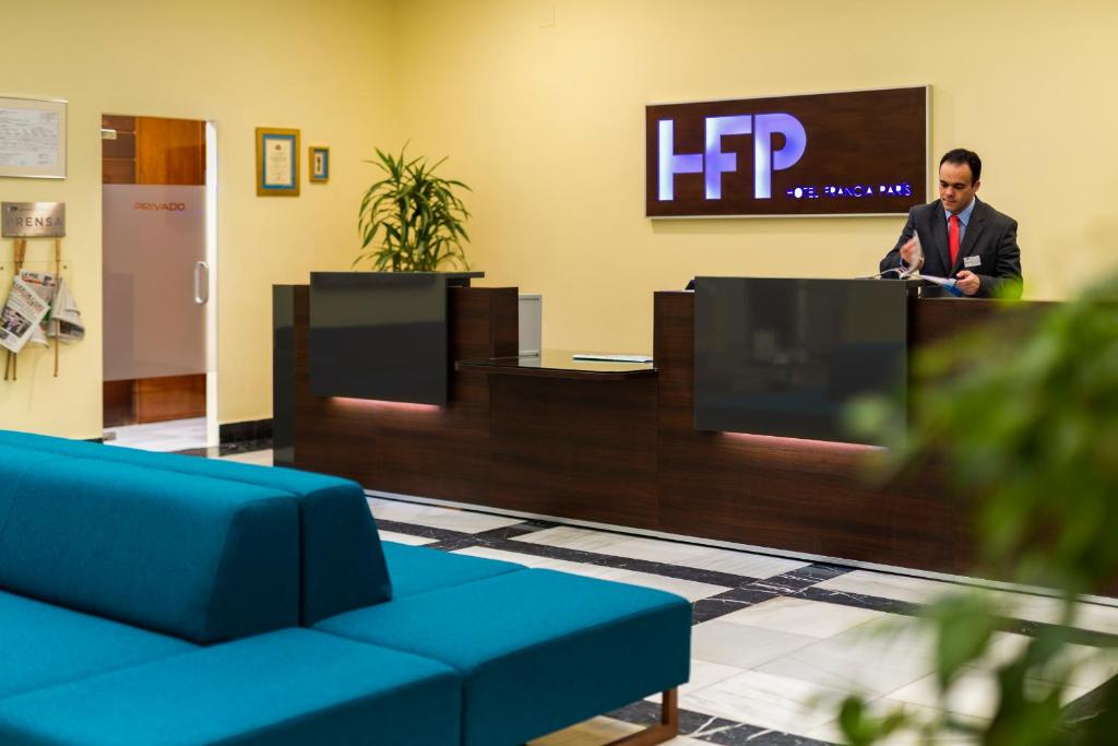 a man standing at a podium in a lobby at Hotel de Francia y París in Cádiz