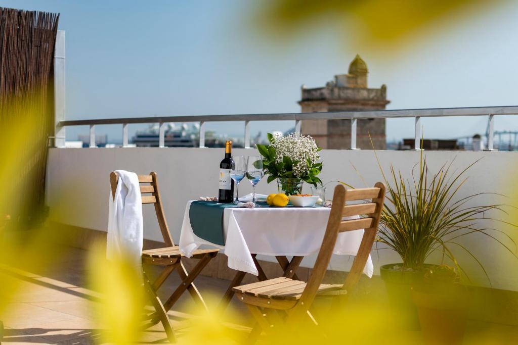 a table with two chairs and a bottle of wine at Hotel de Francia y París in Cádiz