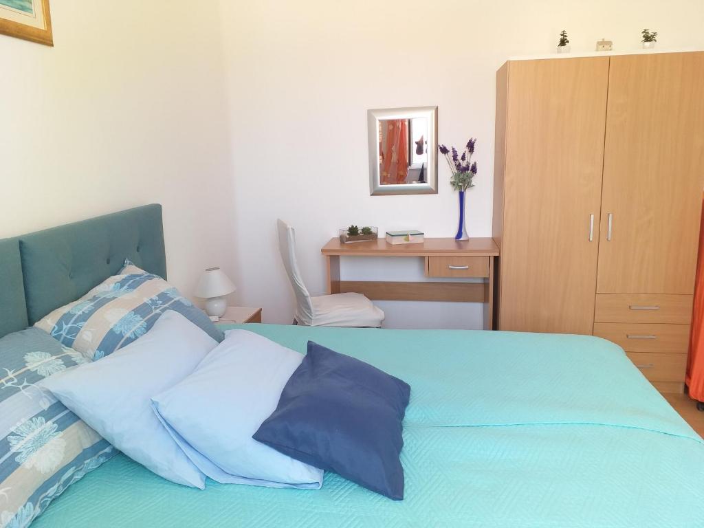 ein Schlafzimmer mit einem blauen Bett mit Kissen und einem Schreibtisch in der Unterkunft Apartment Ana in Split