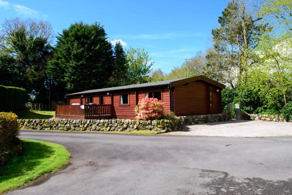 a small cabin with a stone wall next to a road at Kipplochan in Dalbeattie