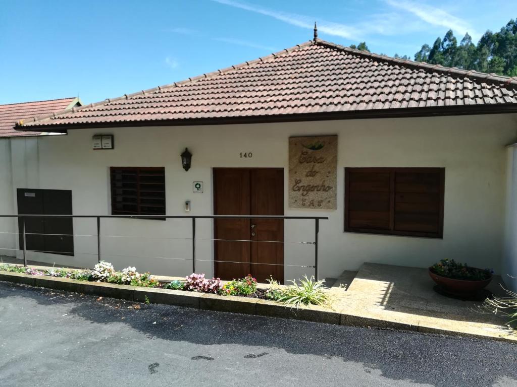 una casa blanca con una puerta y flores delante en Casa do Engenho en Caldas de São Jorge