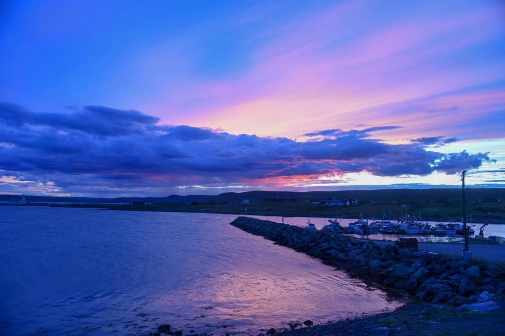 una puesta de sol sobre un cuerpo de agua con un muelle en Varanger Fisherman's Shed, en Varangerbotn