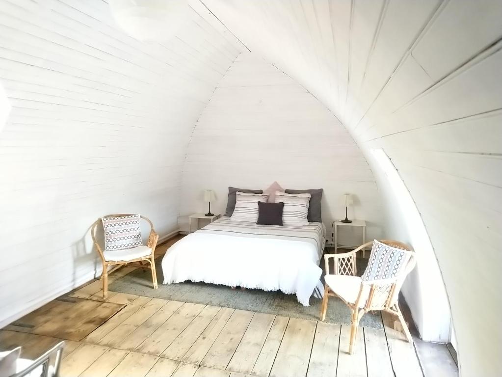 a white bedroom with a bed and two chairs at La Soubeyranne in Mende