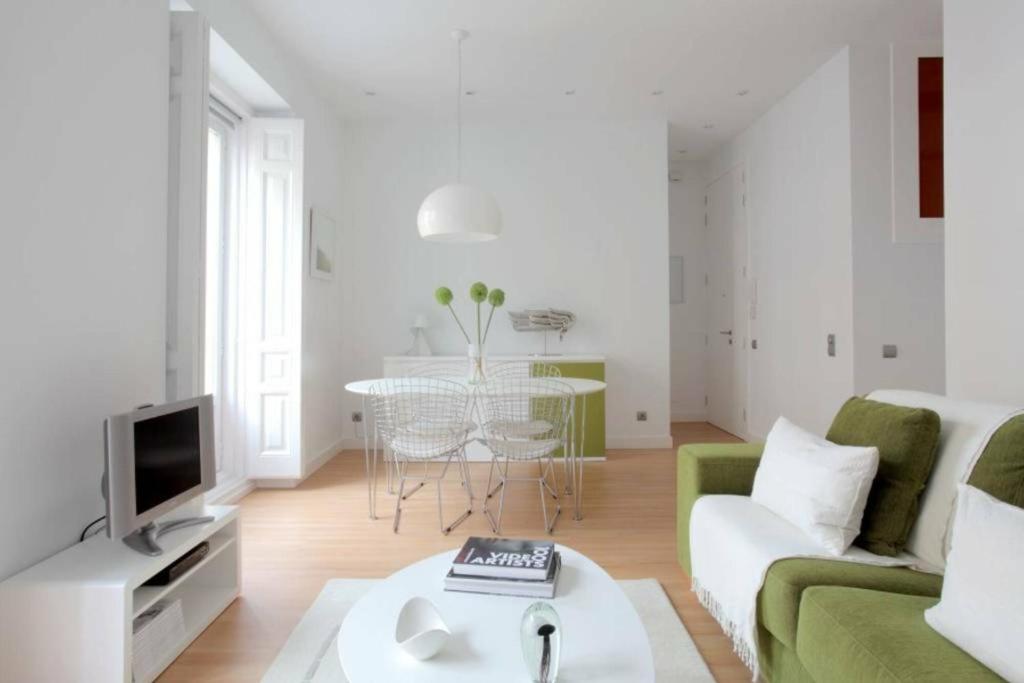 sala de estar con sofá verde y TV en Apartamento Callao, en Madrid