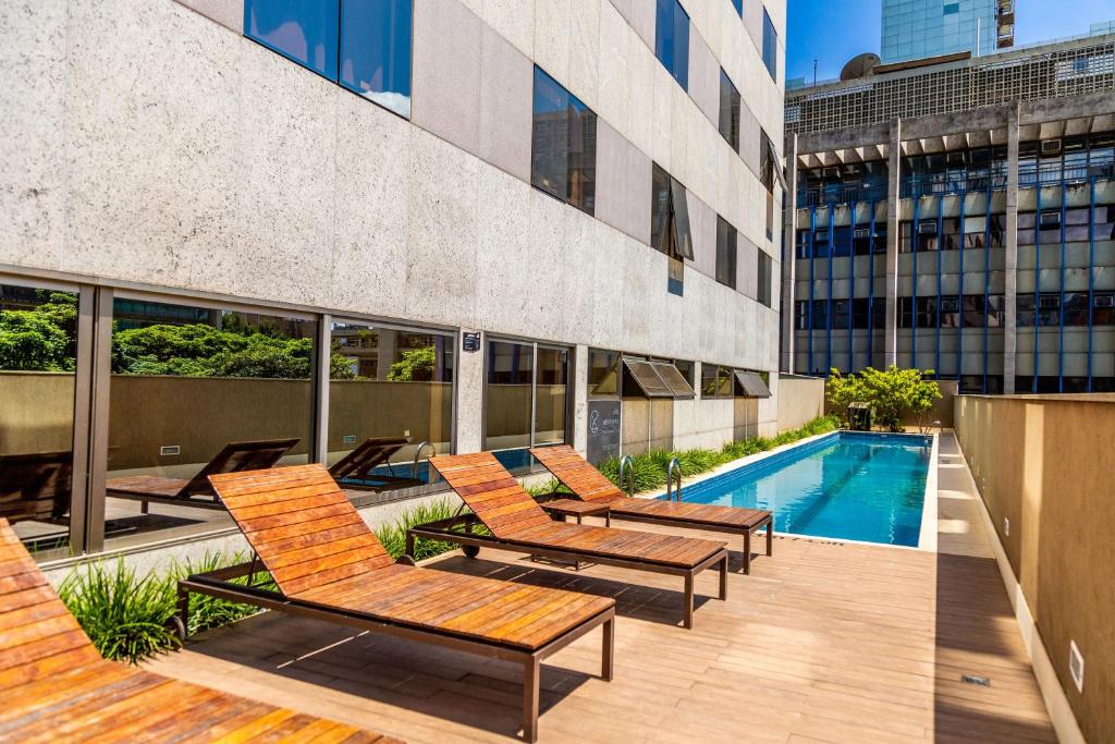 um pátio com cadeiras e uma piscina num edifício em Hilton Garden Inn Belo Horizonte Lourdes em Belo Horizonte