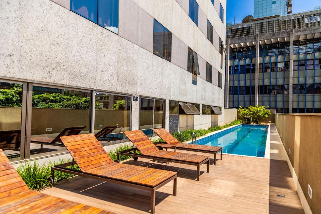 a patio with chairs and a swimming pool on a building at Hilton Garden Inn Belo Horizonte Lourdes in Belo Horizonte