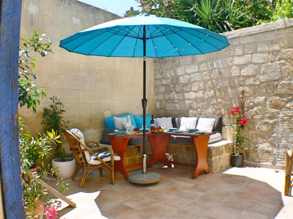 un patio con una mesa con una sombrilla azul en Maison Roxanne & Maisonette in medieval city by Rhodes4vacation en Rodas