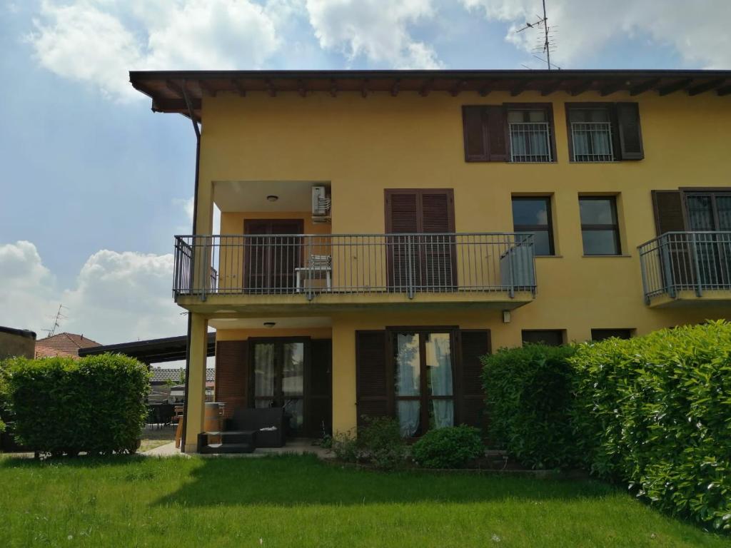 Casa amarilla grande con balcón y matorrales. en Appartamento vicino Malpensa, en Vanzaghello