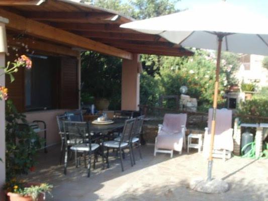 a patio with a table and chairs and an umbrella at Casa Vacanza la terrazza panoramica a 200 mt dal mare in Simius
