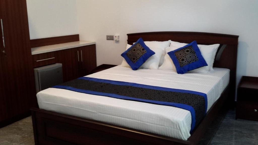 a bedroom with a large bed with blue pillows at Dumi's Shelter Home Stay in Colombo