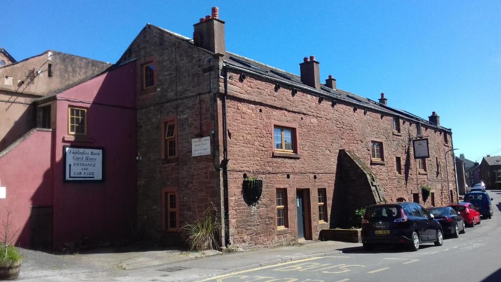 un vecchio edificio di mattoni con macchine parcheggiate di fronte di Fairladies Barn Guest House a St Bees