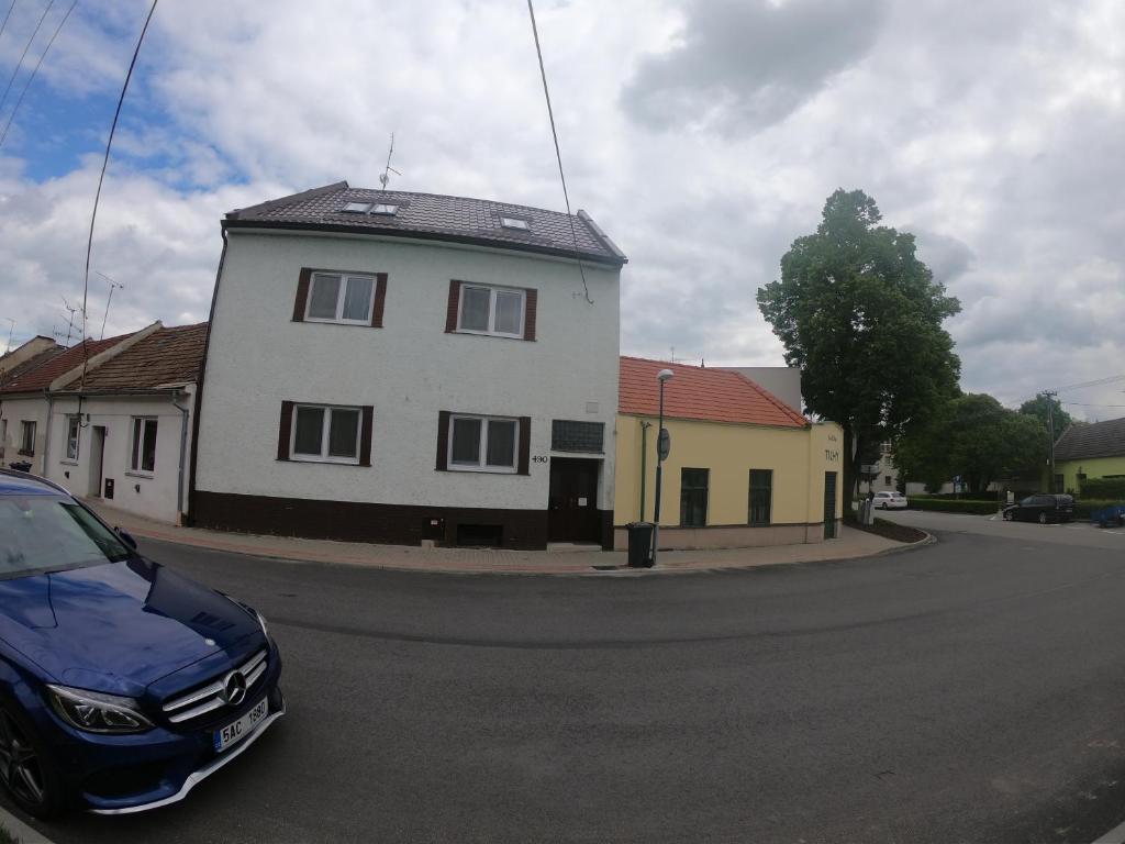 une voiture bleue garée devant une maison blanche dans l'établissement Rodinný Penzion Kyjov, à Kyjov