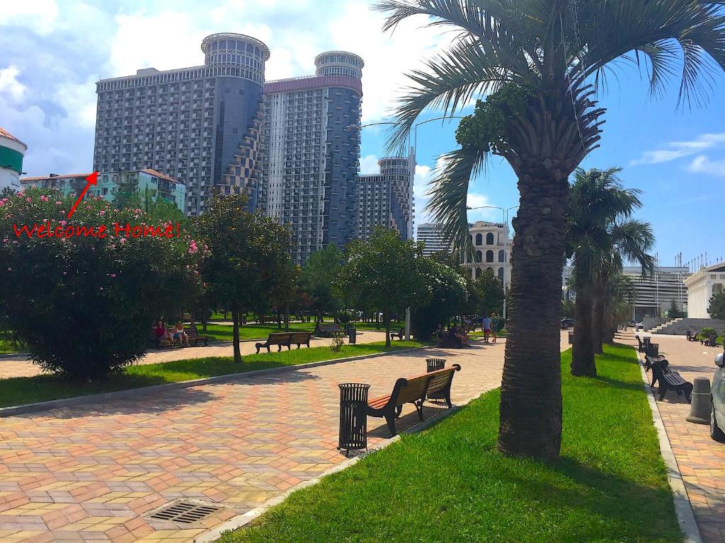 einen Park mit Palmen, Bänken und Gebäuden in der Unterkunft Orbi Sea Towers Apartments in Batumi