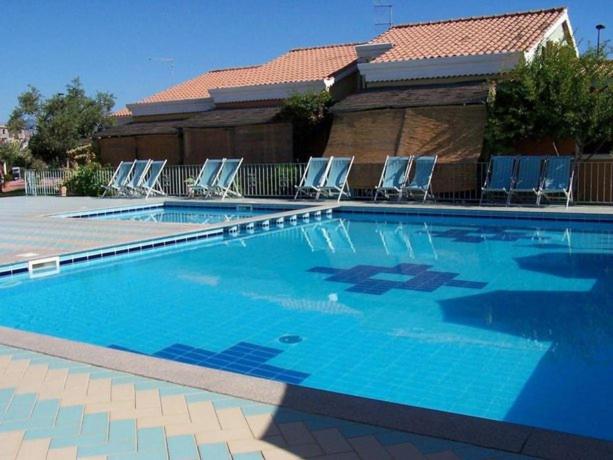 a large swimming pool with chairs and a building at Appartamento presso Residence Verdemare in Àrbatax