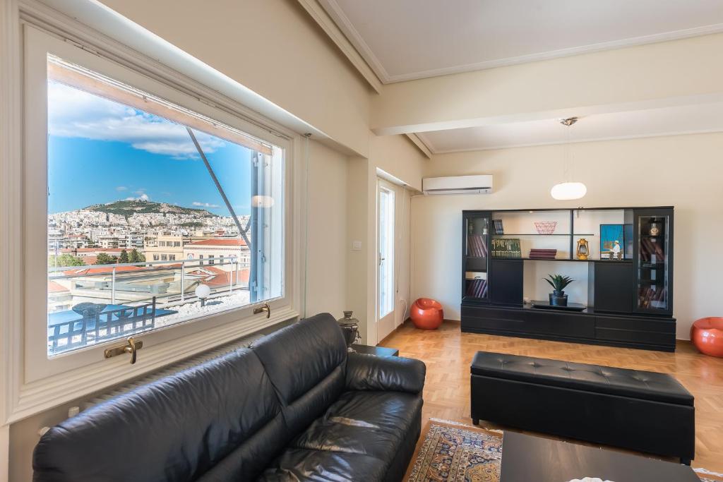 salon ze skórzaną kanapą i dużym oknem w obiekcie ATHENStay Penthouse Suite w Atenach