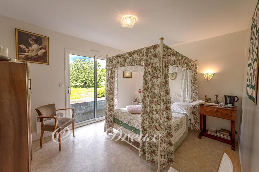 a bedroom with a canopy bed with a table and a desk at ty dreux entre terre et mer in Saint-Thégonnec