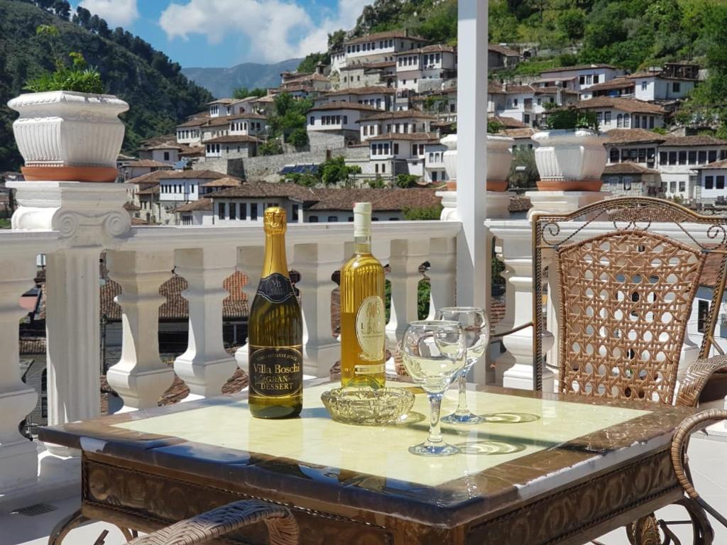 una mesa con botellas de vino y copas en el balcón en Guesthouse Arben Elezi, en Berat