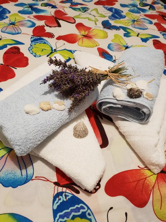 a pile of towels and flowers on a bed at Apartman Dora in Šmrika