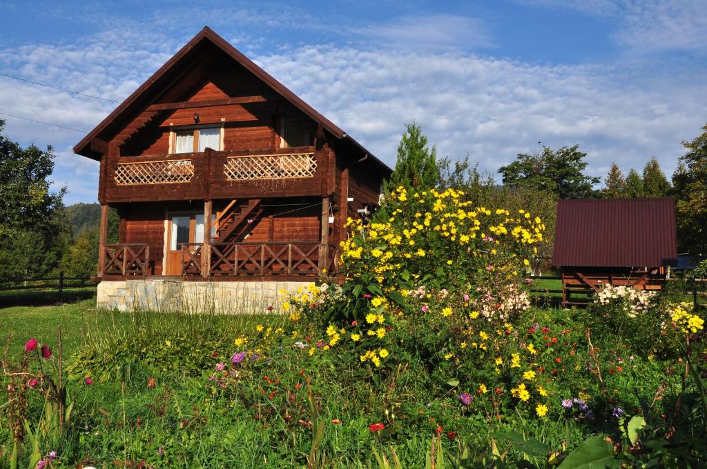 uma casa com um campo de flores em frente em Завітай em Yaremche