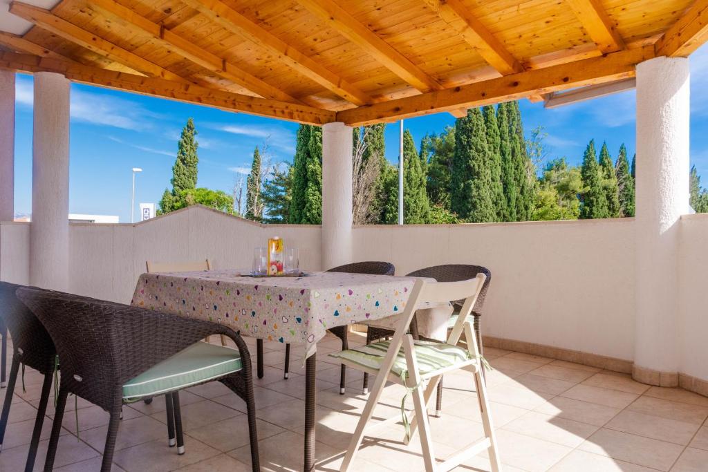 a table and chairs on a patio with a view of trees at Mala Kate Apartments in Kaštela