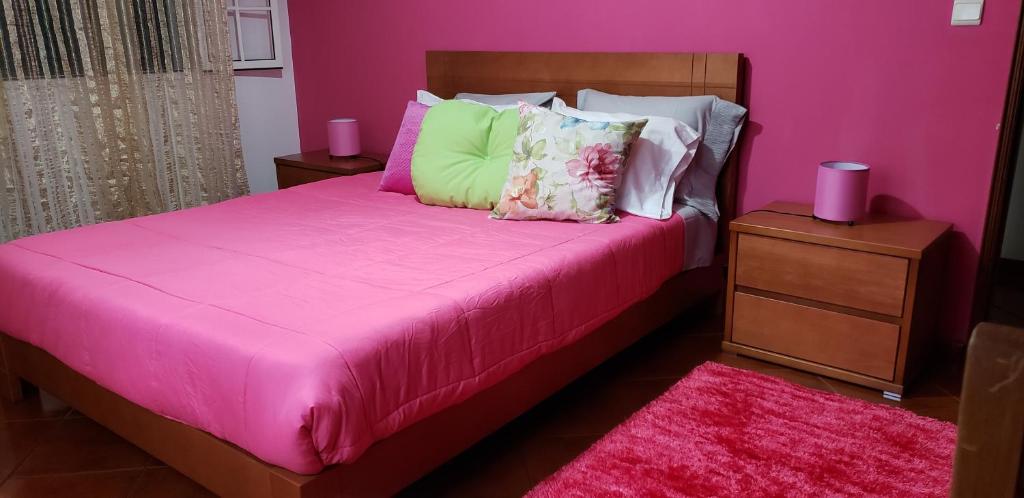 Dormitorio rosa con cama con sábanas y almohadas rosas en Casa da Ribeira, en Povoação