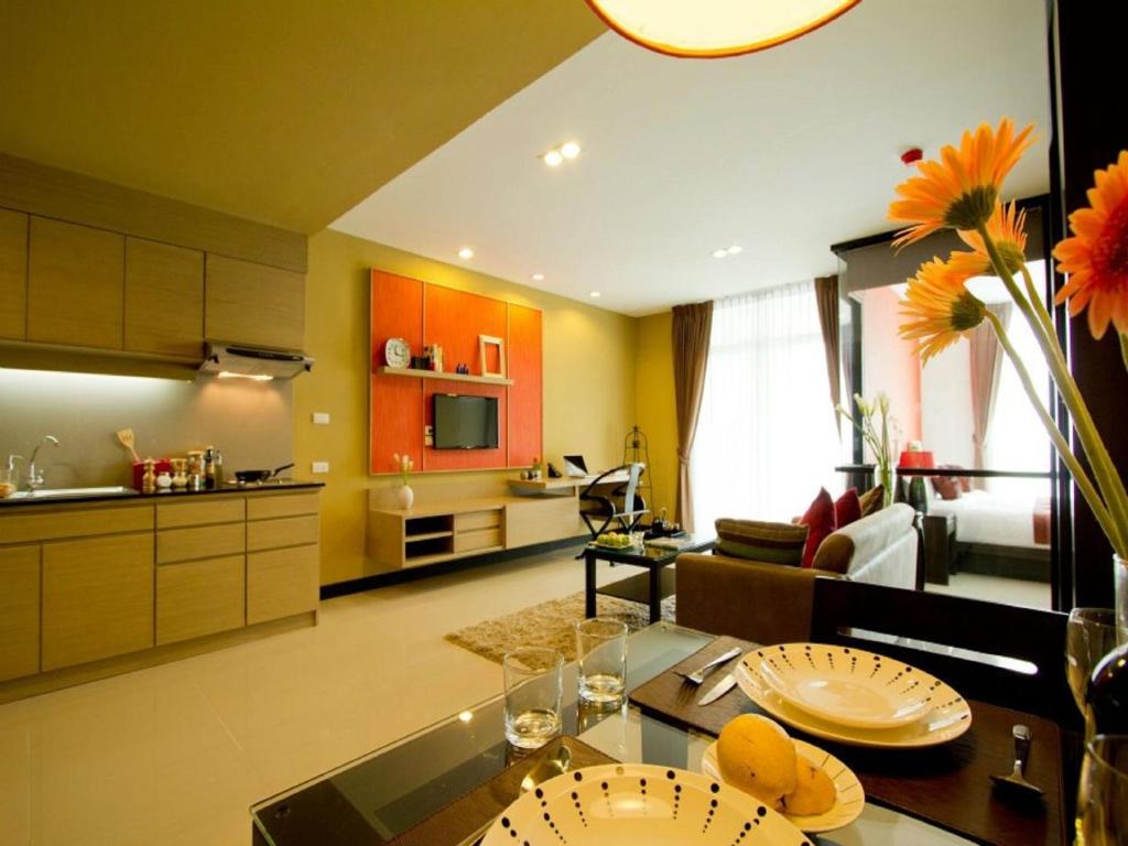 a kitchen and living room with orange cabinets and a table at The Grand Wipanan Residence in Chiang Mai