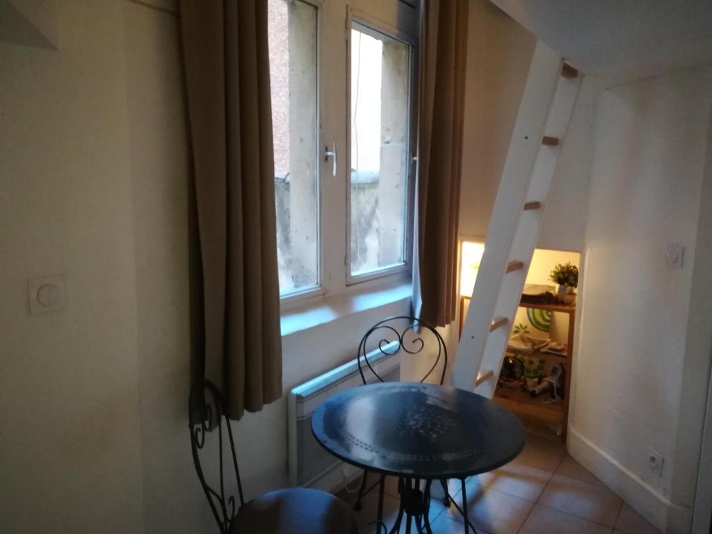 a room with a table and a ladder next to a window at Studio Vieux Lyon in Lyon