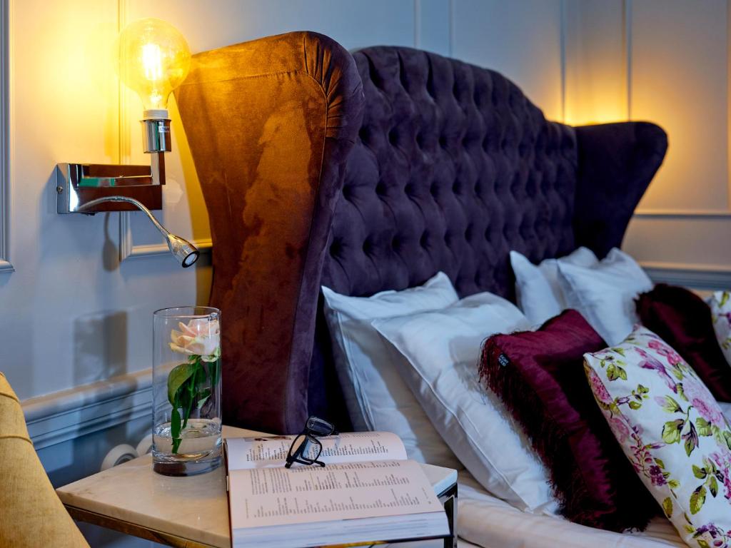 Una cama con una mesa con un jarrón de flores. en Grenna Hotell en Gränna
