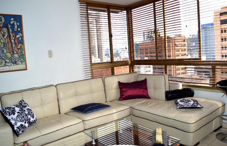una sala de estar con un sofá blanco con almohadas. en Confortable apto tipo Suite/ Turismo Relax, en Caracas