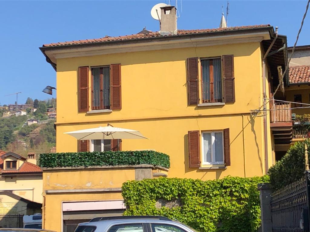 a yellow house with an umbrella in front of it at Casa L'Aquila in Como