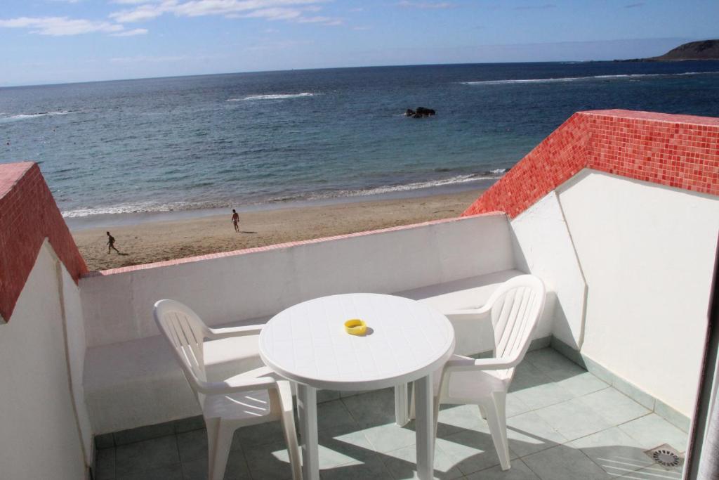 una mesa y sillas en un balcón con vistas a la playa en Carus Flat, en Las Palmas de Gran Canaria