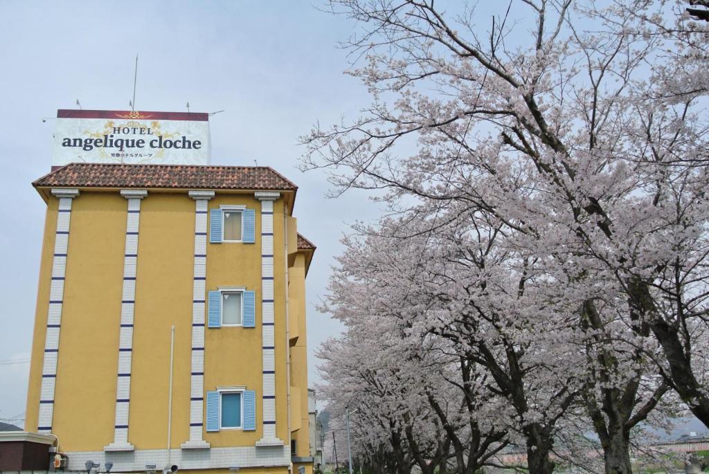 un edificio amarillo con un cartel encima en アンジェリーククロッシュ 男塾ホテルグループ, en Himeji