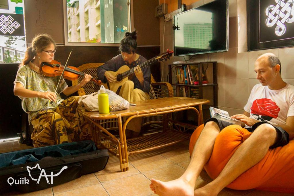 eine Gruppe von Menschen, die in einem Zimmer Musik spielen in der Unterkunft QuiikCat in Kuching