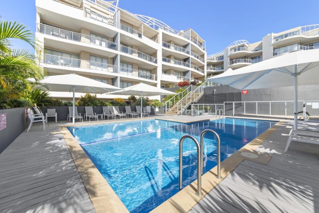 a swimming pool with chairs and umbrellas next to a building at Cote D'Azur Resort in Nelson Bay