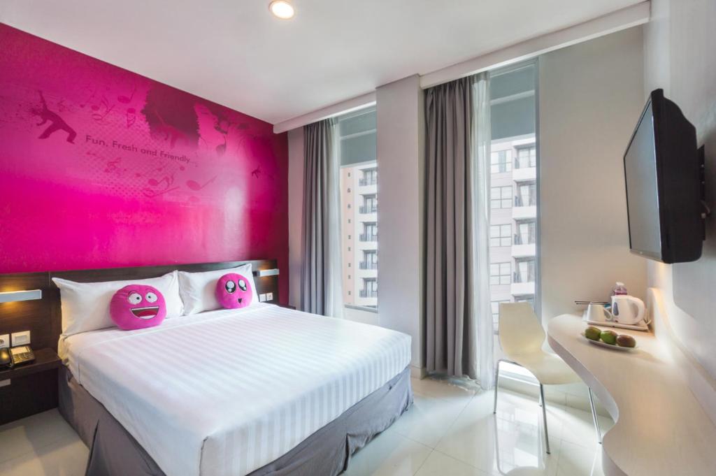 a bedroom with pink walls and a bed with hello kitty pillows at favehotel Gatot Subroto Jakarta in Jakarta