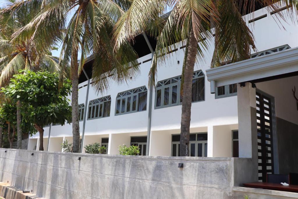 Un edificio blanco con palmeras delante. en Tangalle Rest House, en Tangalle
