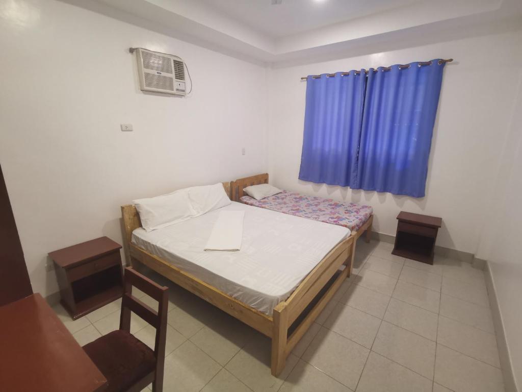 a small bedroom with a bed and a blue curtain at CafeMare Rooms in Bantayan Island