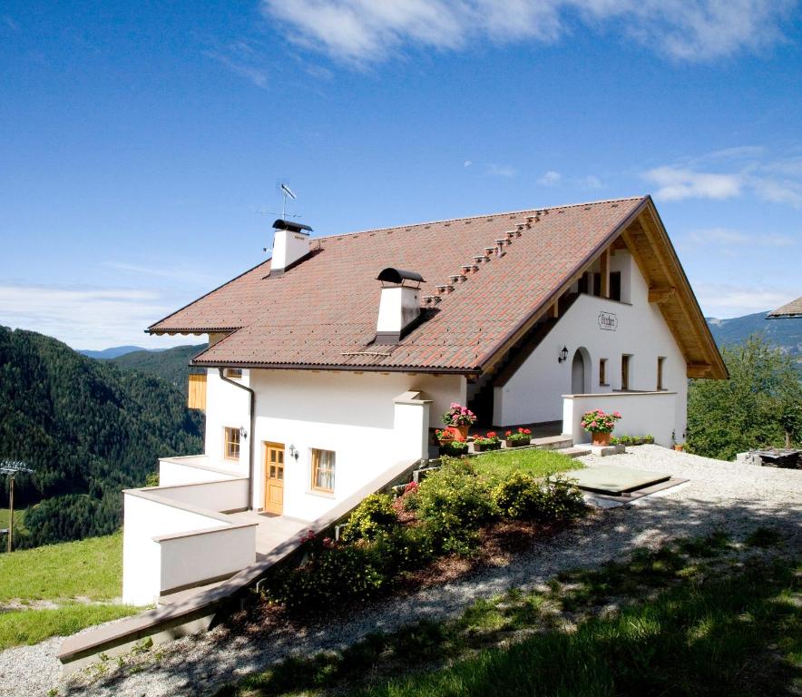 a white house with a brown roof on a hill at Appartment Kircherhof in Laion