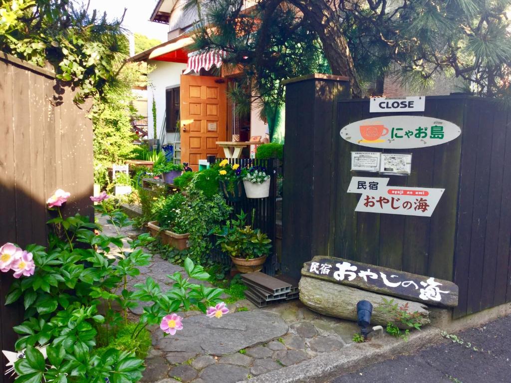 een tuin met bloemen en borden op een hek bij Oyajino Umi in Naoshima