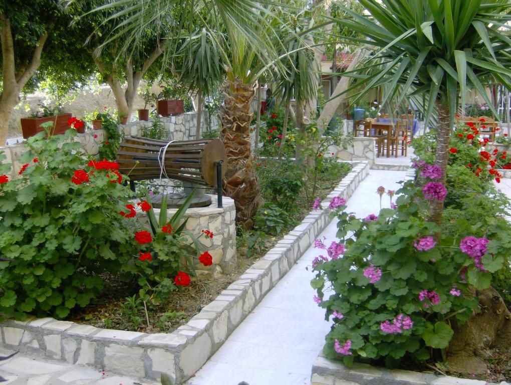 un jardín con flores, un banco y palmeras en Villa Costas - Popi, en Sívas