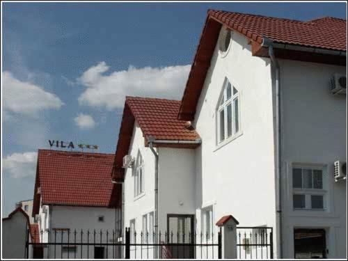 a white building with red roofs and a fence at Vila Casa Alesiv in Cluj-Napoca