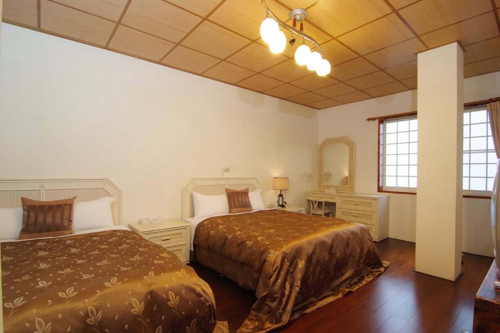 a bedroom with two beds and a desk and two windows at Cing Jing Homeland Resort Villa in Ren&#39;ai