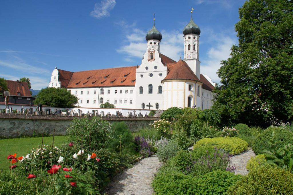 a building with two towers and a garden with flowers at Kloster Benediktbeuern - Gästehaus der Salesianer Don Bosco in Benediktbeuern