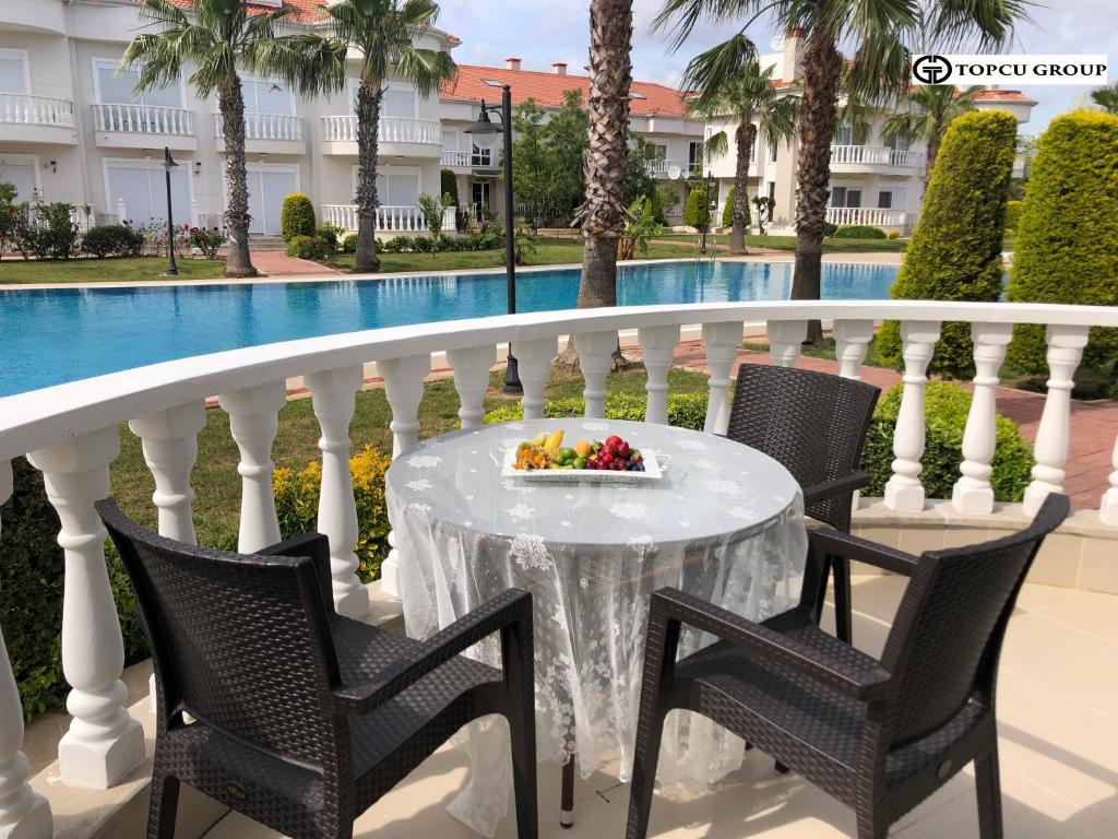 una mesa y sillas en un balcón con piscina en Belek Golf Village - Villa with shared pool, en Belek