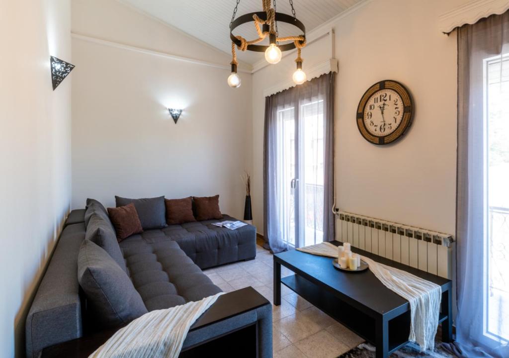 a living room with a couch and a clock on the wall at Andria City Apartment in Zakynthos