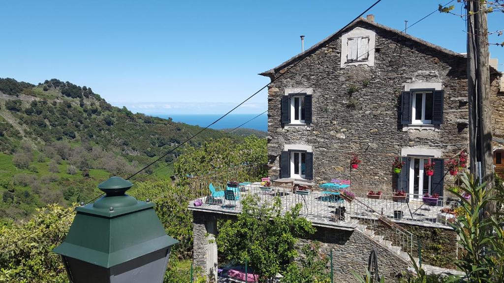 English Club in Corsica A في Porri: منزل حجري قديم بسقف أخضر