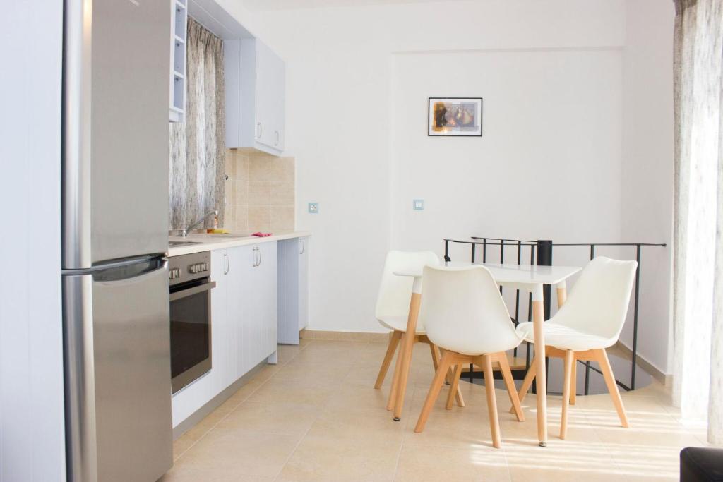 a kitchen with white appliances and a table and chairs at Sahas Apartments in Mikonos