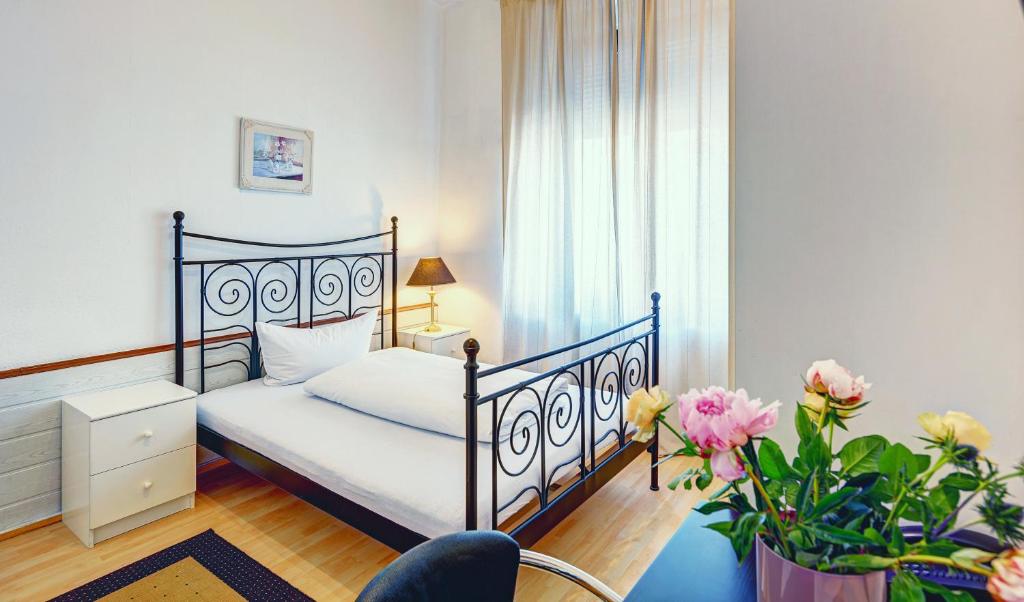 a bedroom with a bed and a table and flowers at Hotel Cornelia in Bad Nauheim