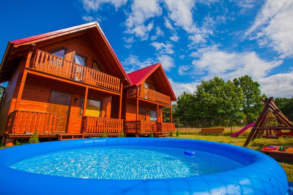 a house with a pool in front of it at Domki Zacisze in Ostrowo